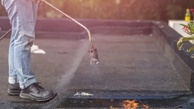 Pose d'une membrane d'étanchéité au chalumeau sur un toit-terrasse